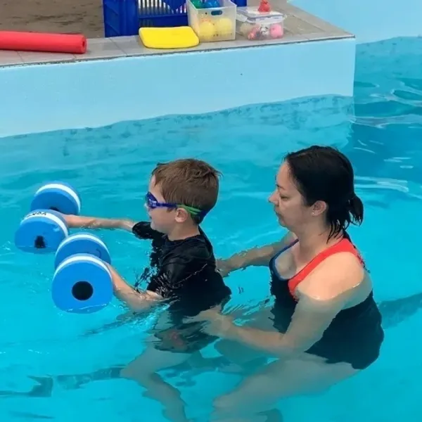Child participating in aquatic physiotherapy with a therapist